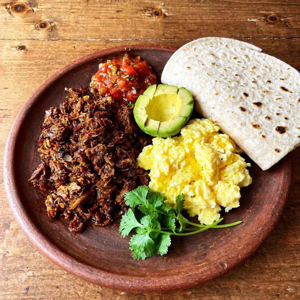 Carnitas breakfast platter with sides and garnishes.