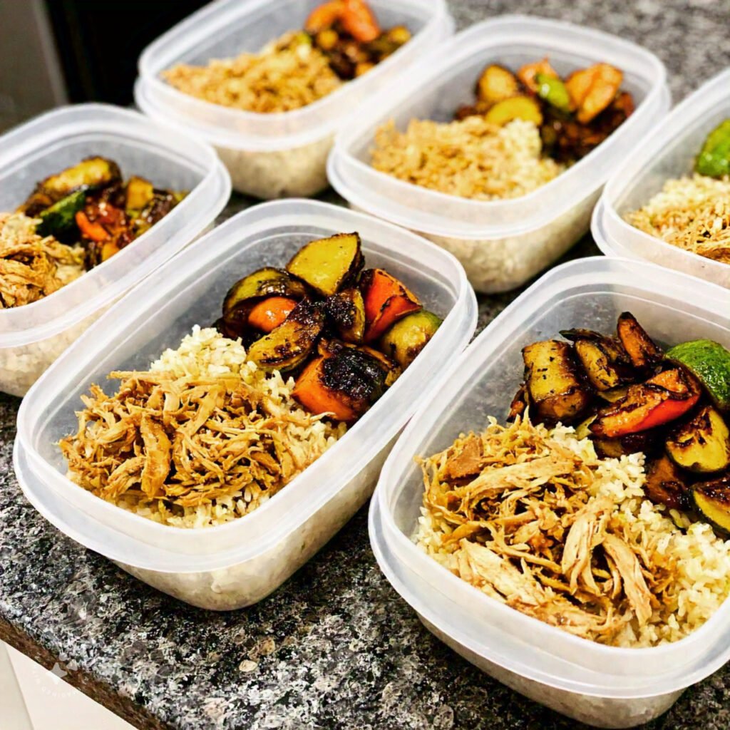 Containers of shredded chicken and assorted vegetables for meal prep.  