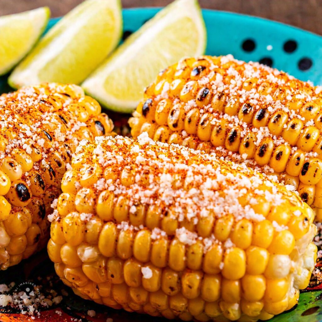 Grilled corn on the cob slathered in creamy sauce, topped with chili powder and crumbled cheese.