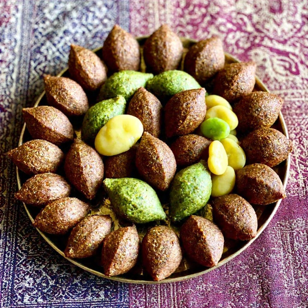 Various regional styles of kibbeh and falafel on a serving platter, showcasing unique shapes and ingredients.